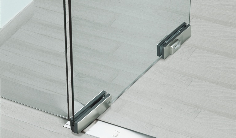 Ổ khóa cửa kính kẹp bản lề sàn được lắp ở góc dưới hoặc cạnh dưới của cánh kính, gần mặt sàn.